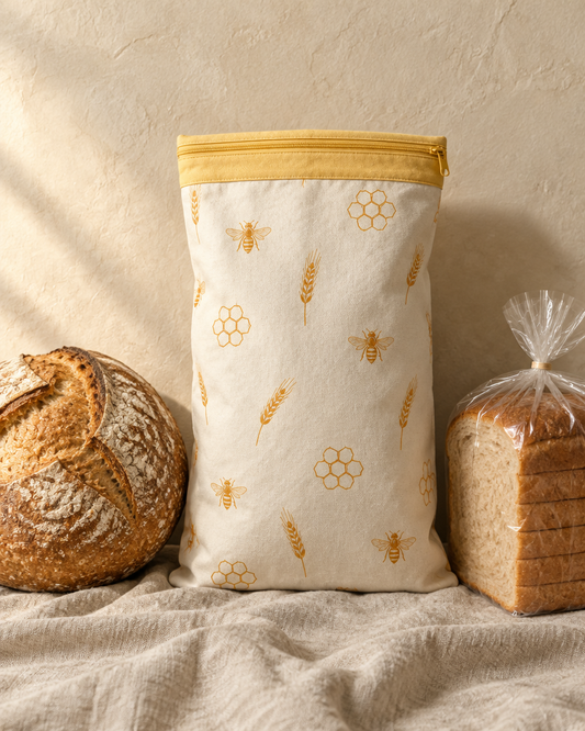 A sourdough boule and a sliced loaf beside a cloth bread bag