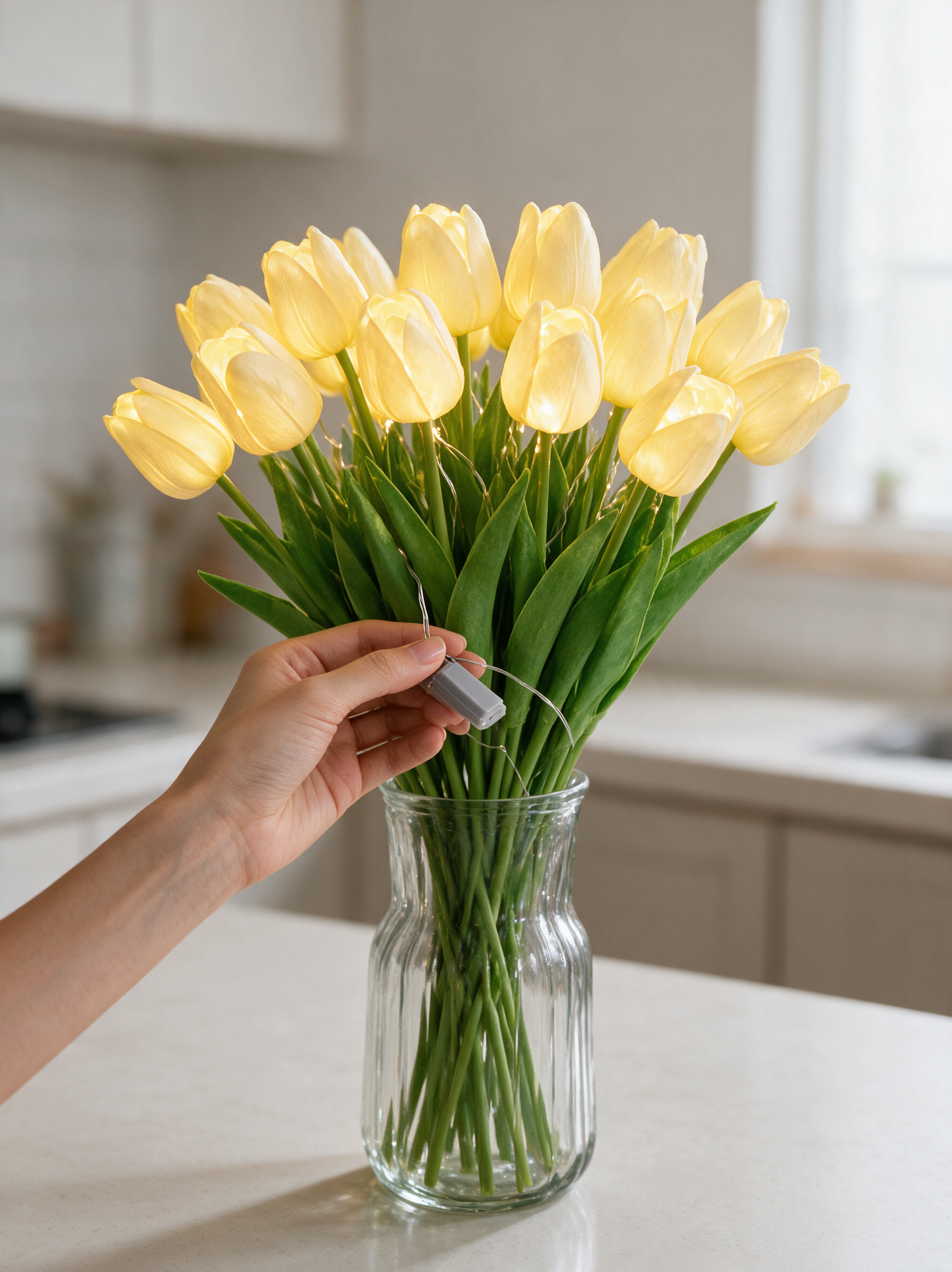 A hand lifting the battery box from among the tulip stems
