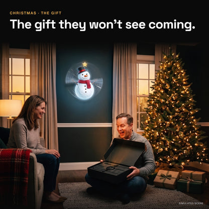 A man opens a black gift box under the Christmas tree while a hologram snowman glows on the wall