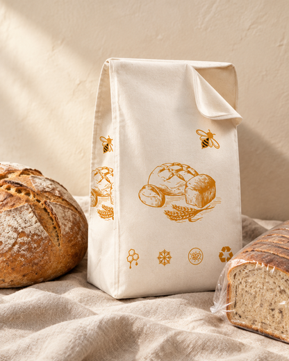 The bread bag beside a sourdough boule and a sliced loaf for scale