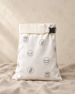 Washday beeswax bread bag in plain cotton with grey care symbols, standing on linen