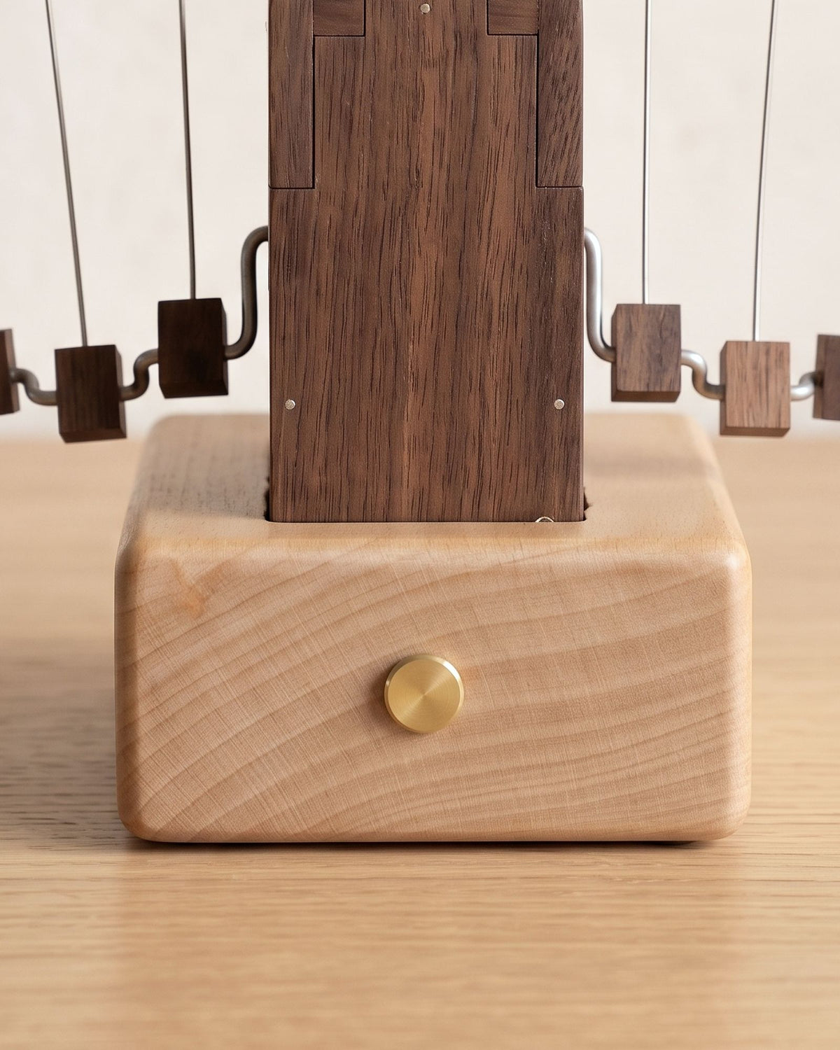 Close-up of the beech base with its brass push button under the black walnut box