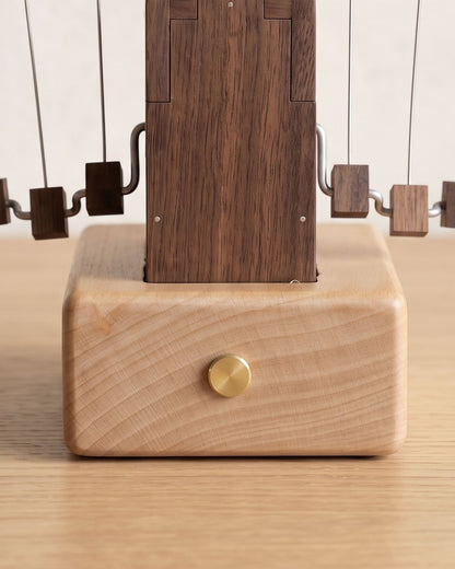 Close-up of the beech base with its brass push button under the black walnut box