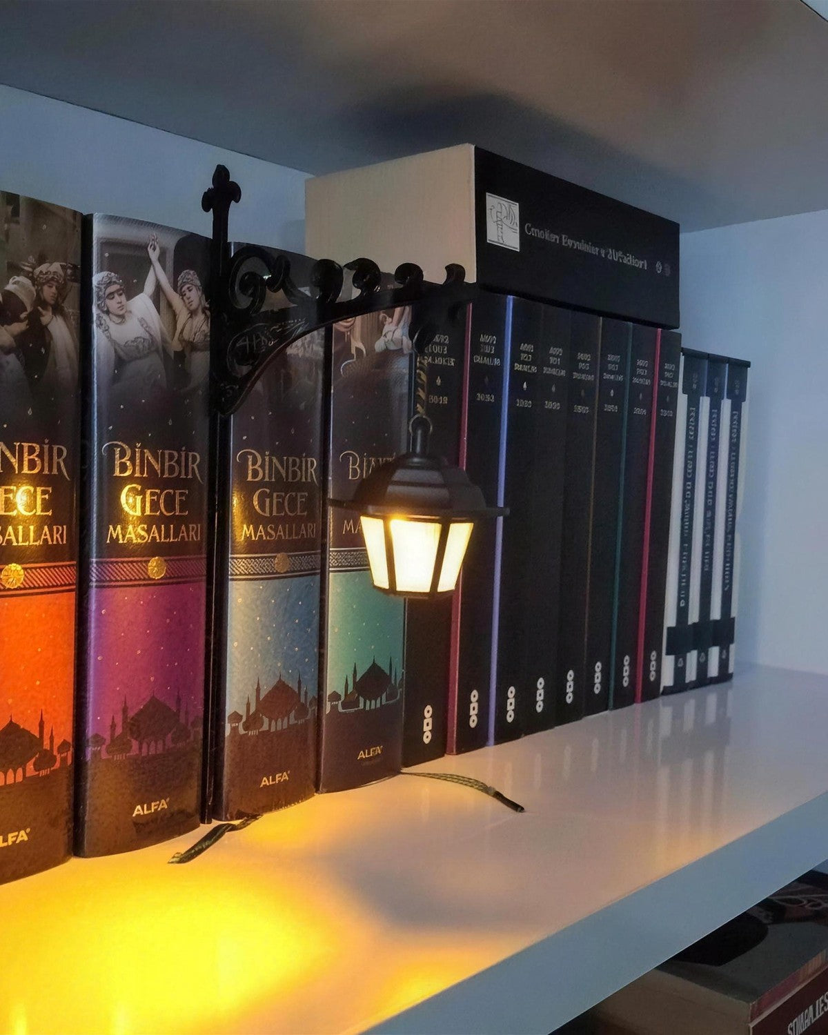 Mini Library Lantern lit on a bookshelf, warm light across the spines