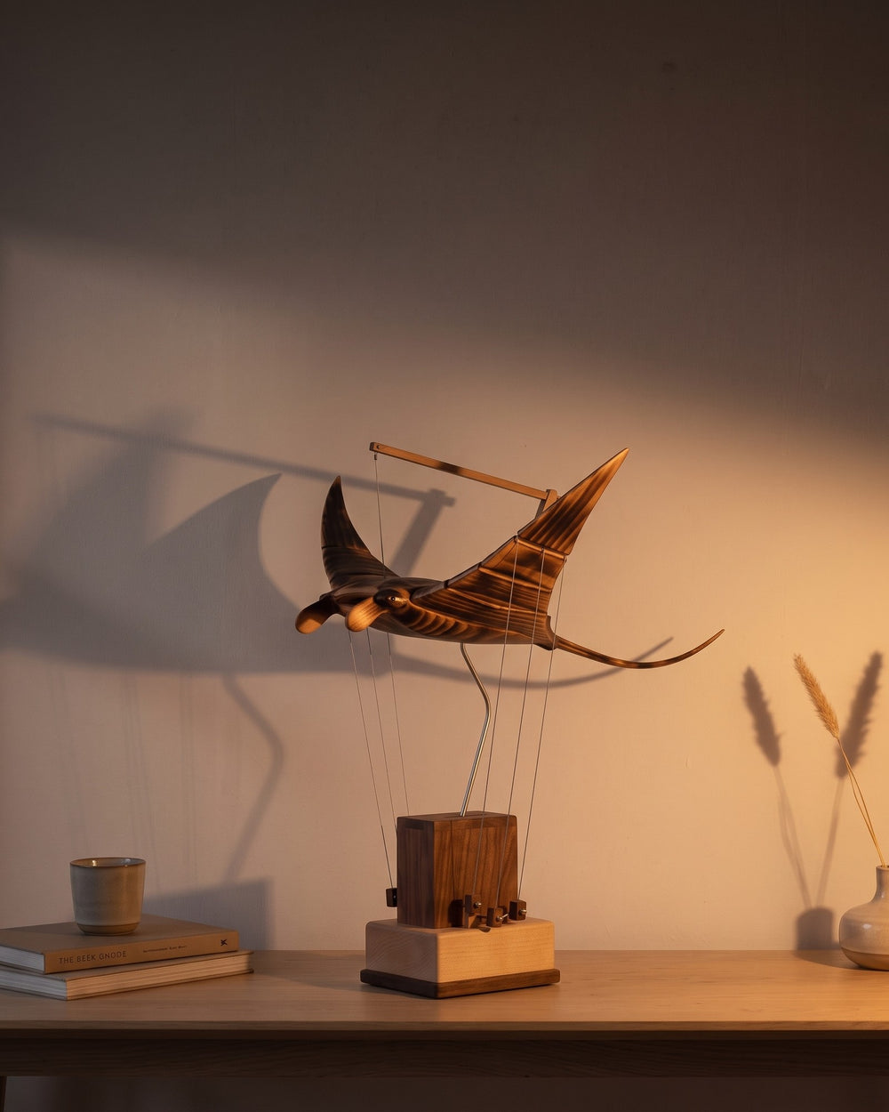 The same table at night, one lamp lit, the ray throwing a long shadow up the wall